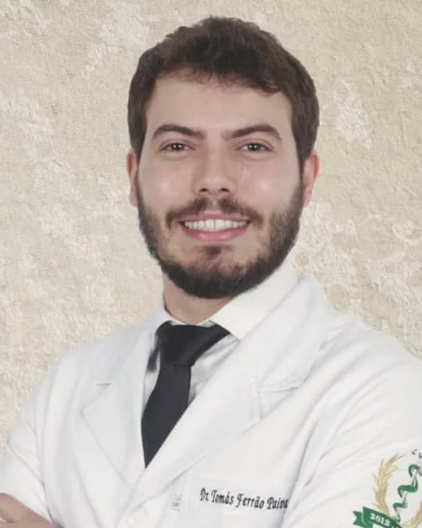 Retrato do Dr. Tomás Ferrão Paiva, de jaleco branco e gravata, sorrindo, com os braços cruzados